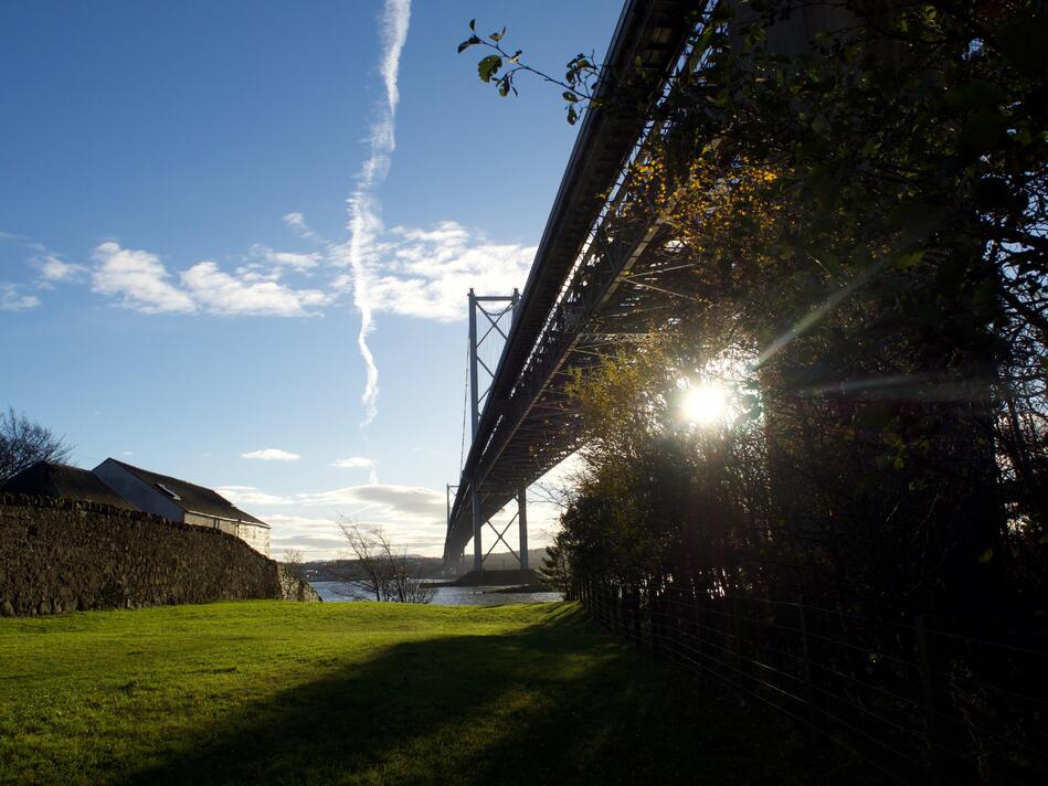 The silhouette of a bridge on the right, with green grass and water visible.