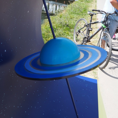 A close-up photo of a blue planet with a dark blue disk intersecting the equator, representing the rings of Saturn.